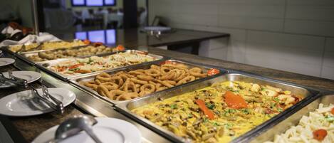 A buffet with various dishes including pasta, salads, and fried items.