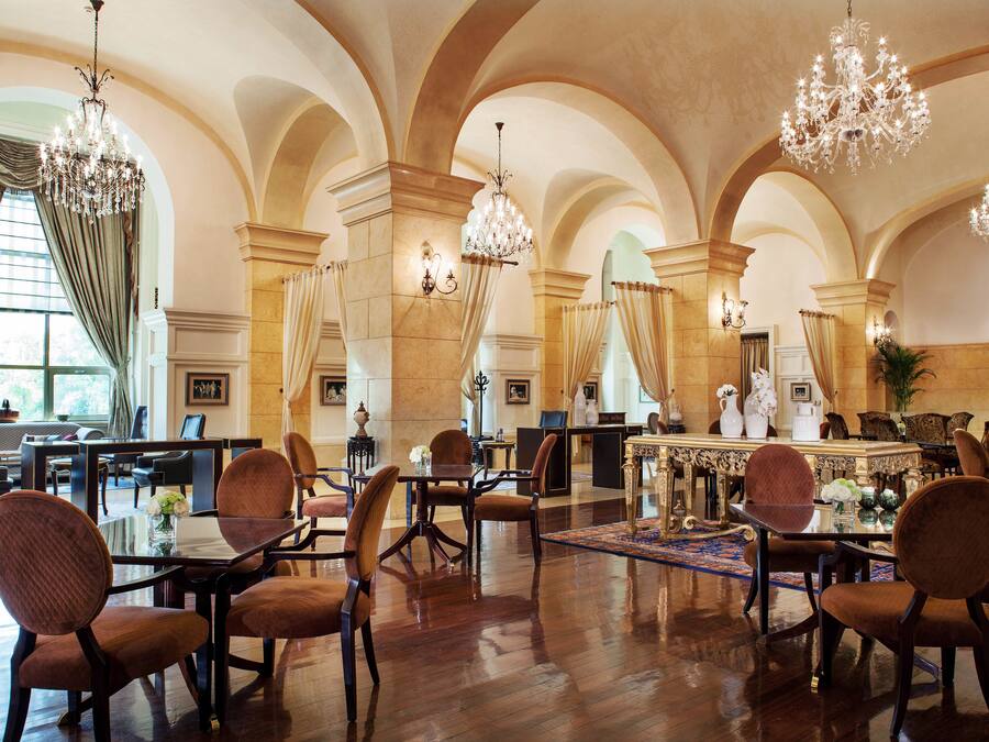 Un vestíbulo amplio con techos altos, candelabros y una zona de bar central.