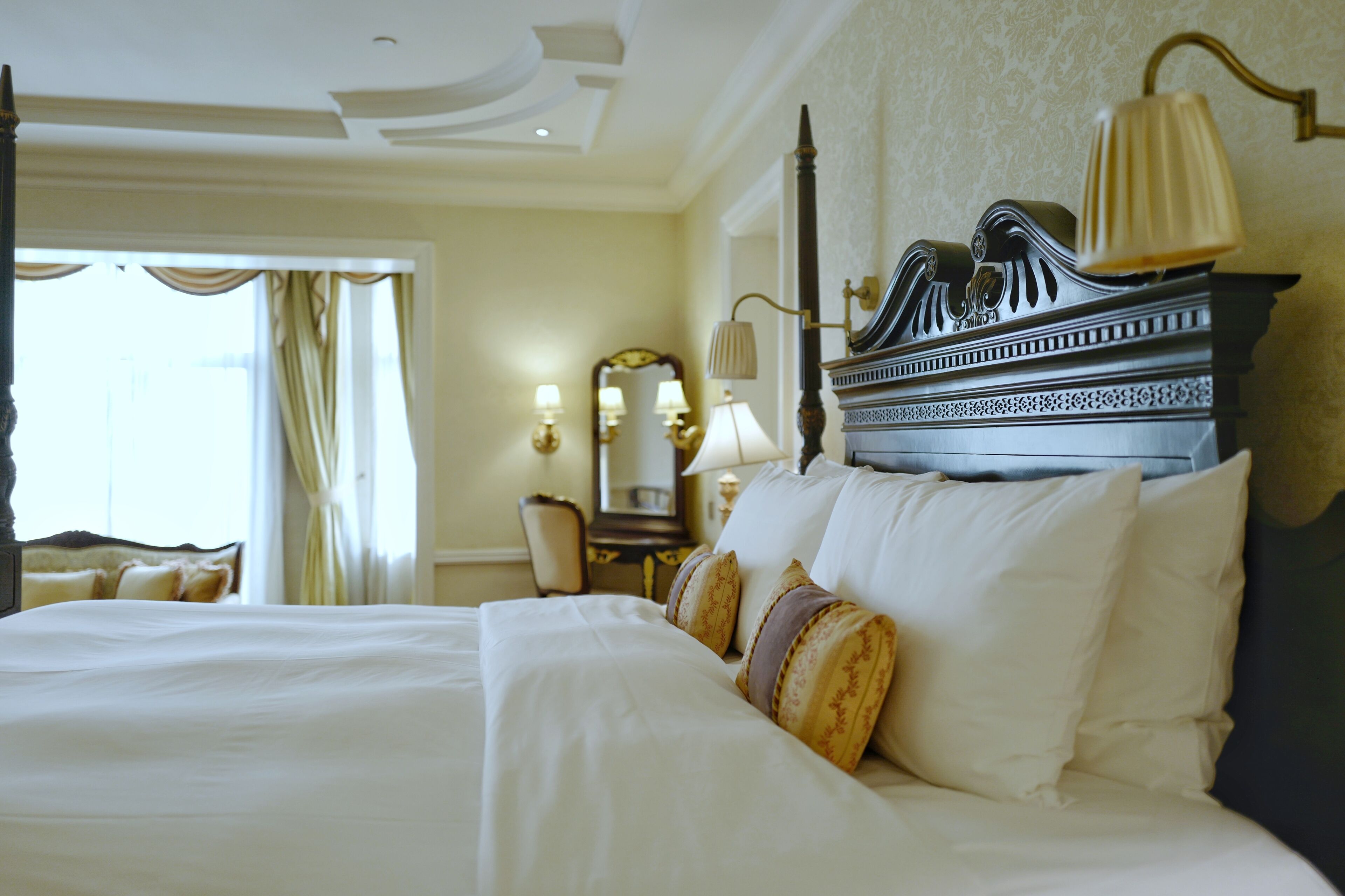 A hotel room with a large bed, a nightstand, a mirror, and a lamp.