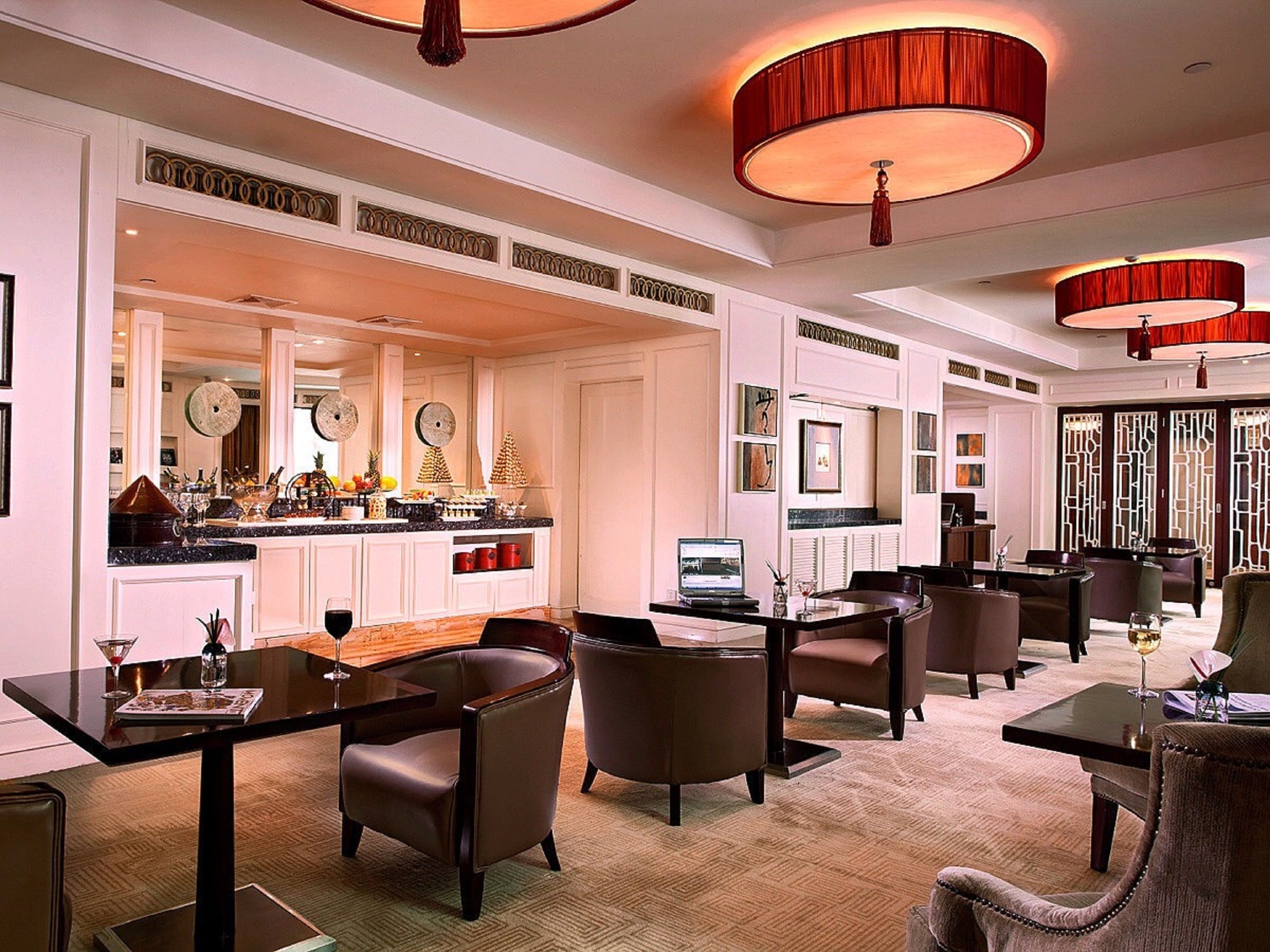 A spacious hotel lobby with a central bar area, multiple seating arrangements, and a modern design.