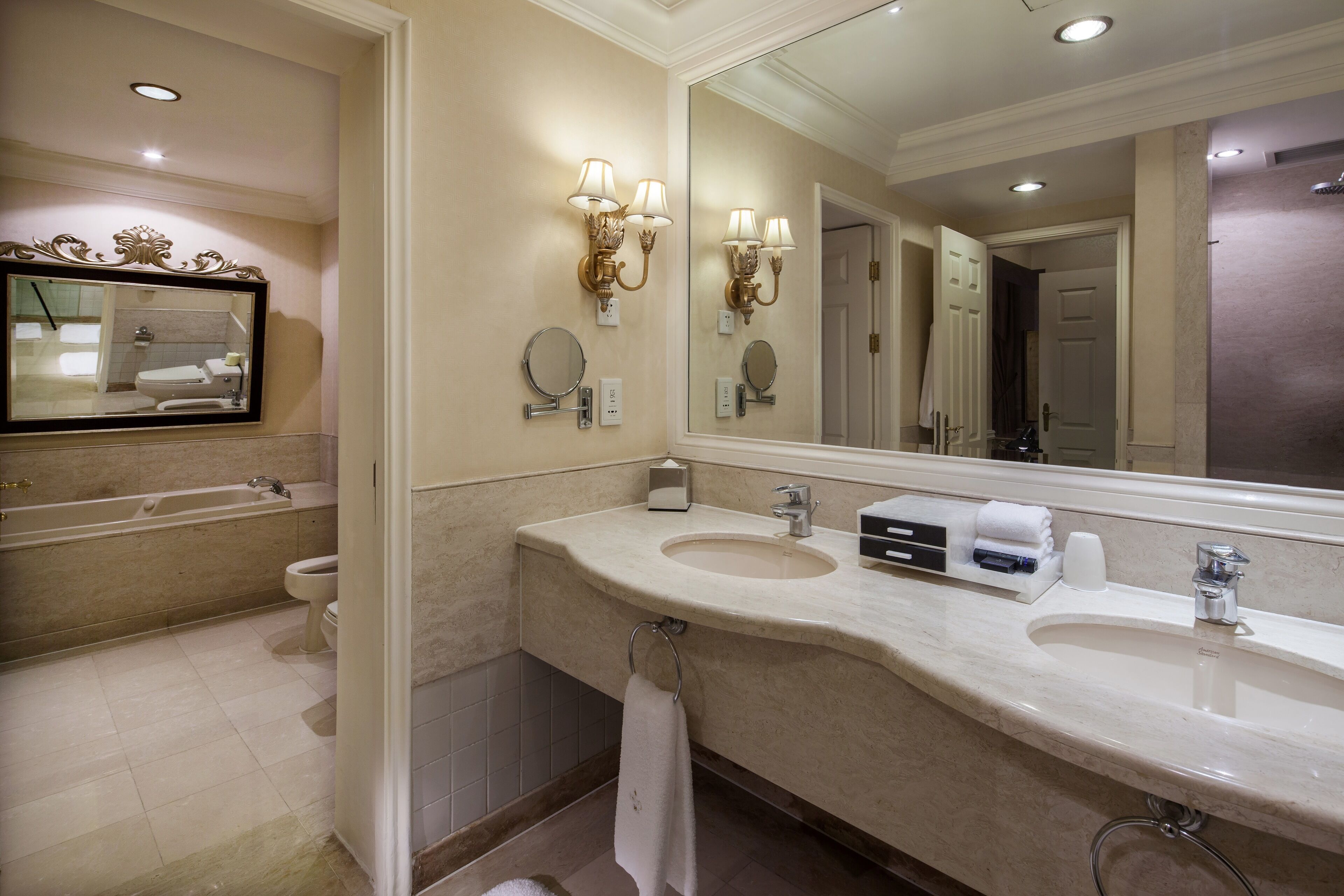 A modern bathroom with a double sink, a large mirror, and a bathtub.