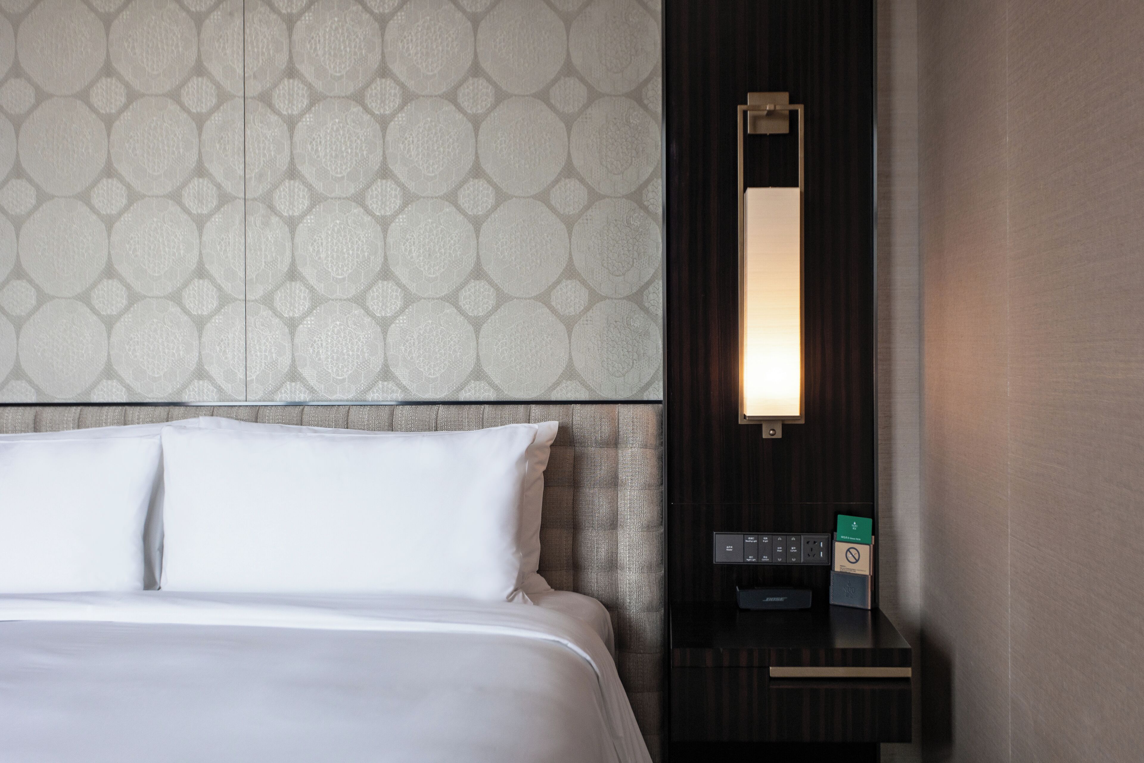 A hotel room with a bed, a nightstand, and a wall-mounted mirror.