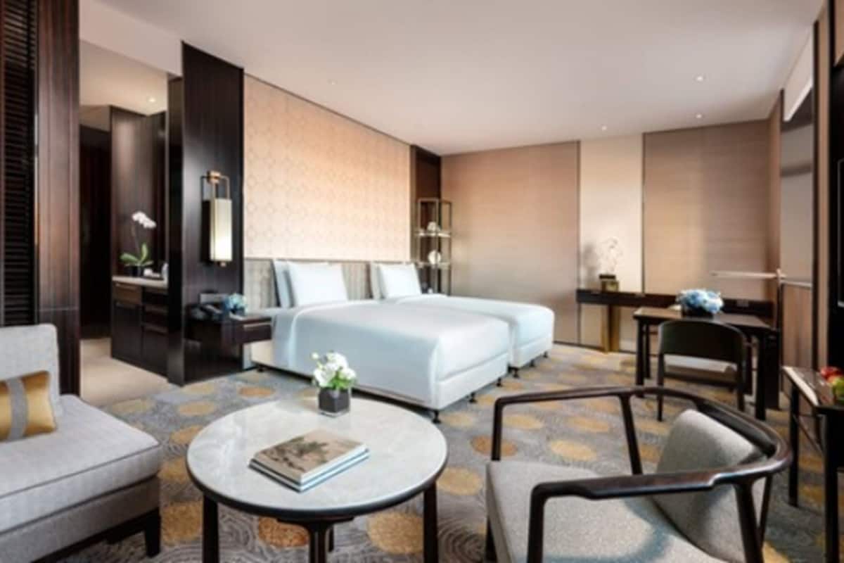 A hotel room with a large bed, two bedside tables, a desk, a chair, and a sofa.
