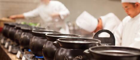 A row of black pots with floral designs, likely used for cooking, in a kitchen setting.