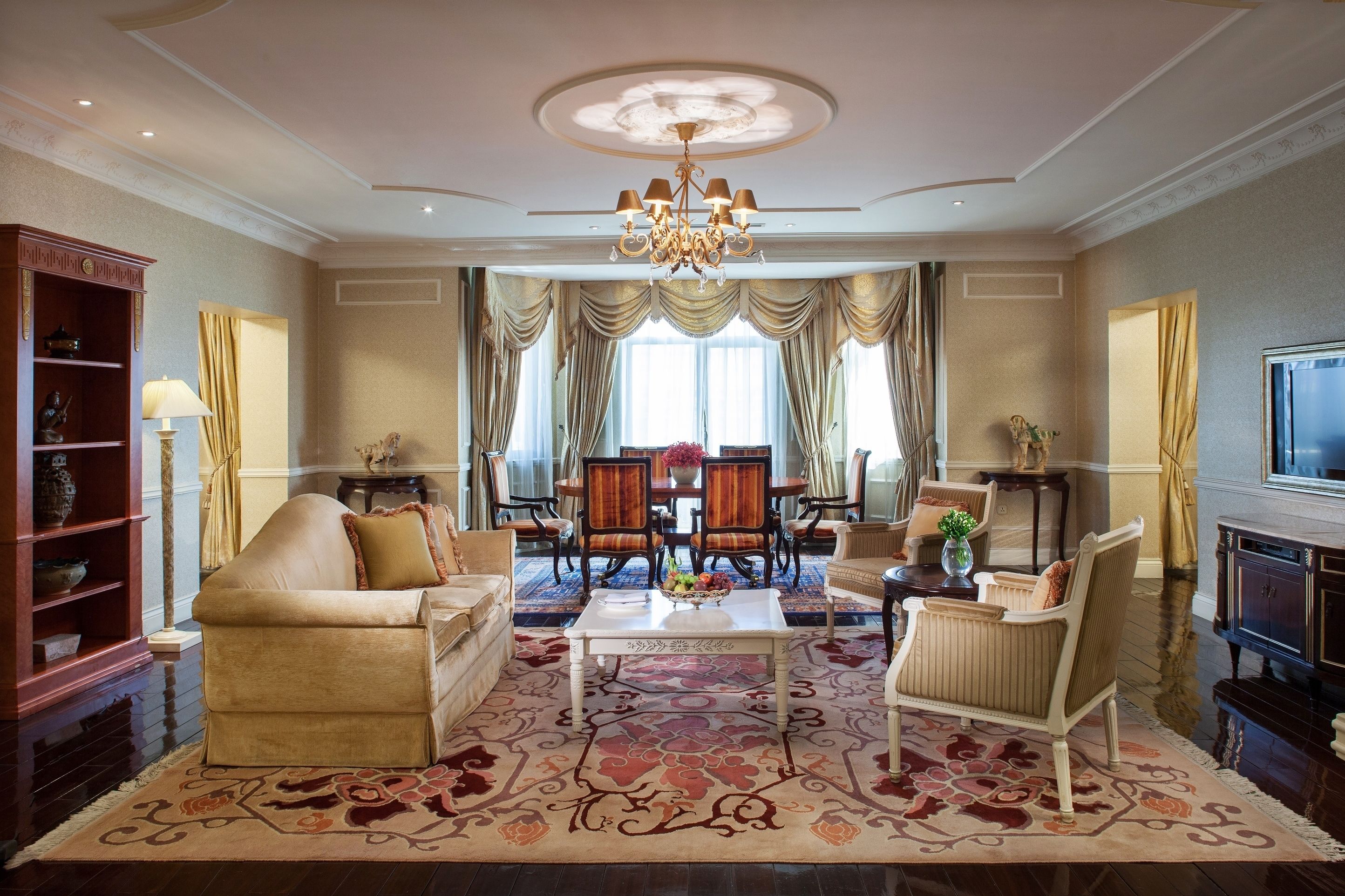 A spacious living room with a chandelier, a coffee table, and a television.