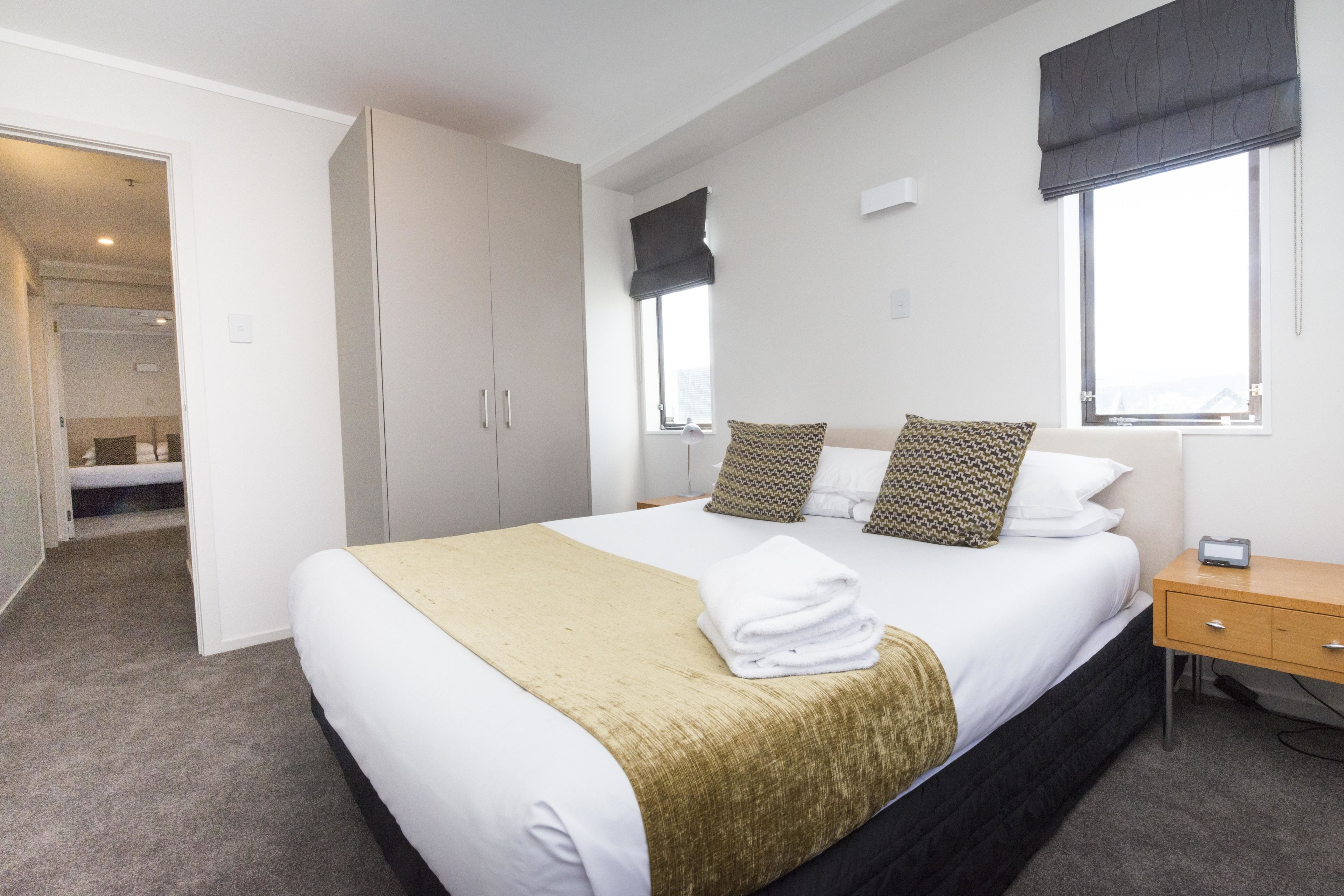 A hotel room with a large bed, a bedside table, a wardrobe, and a window with curtains.