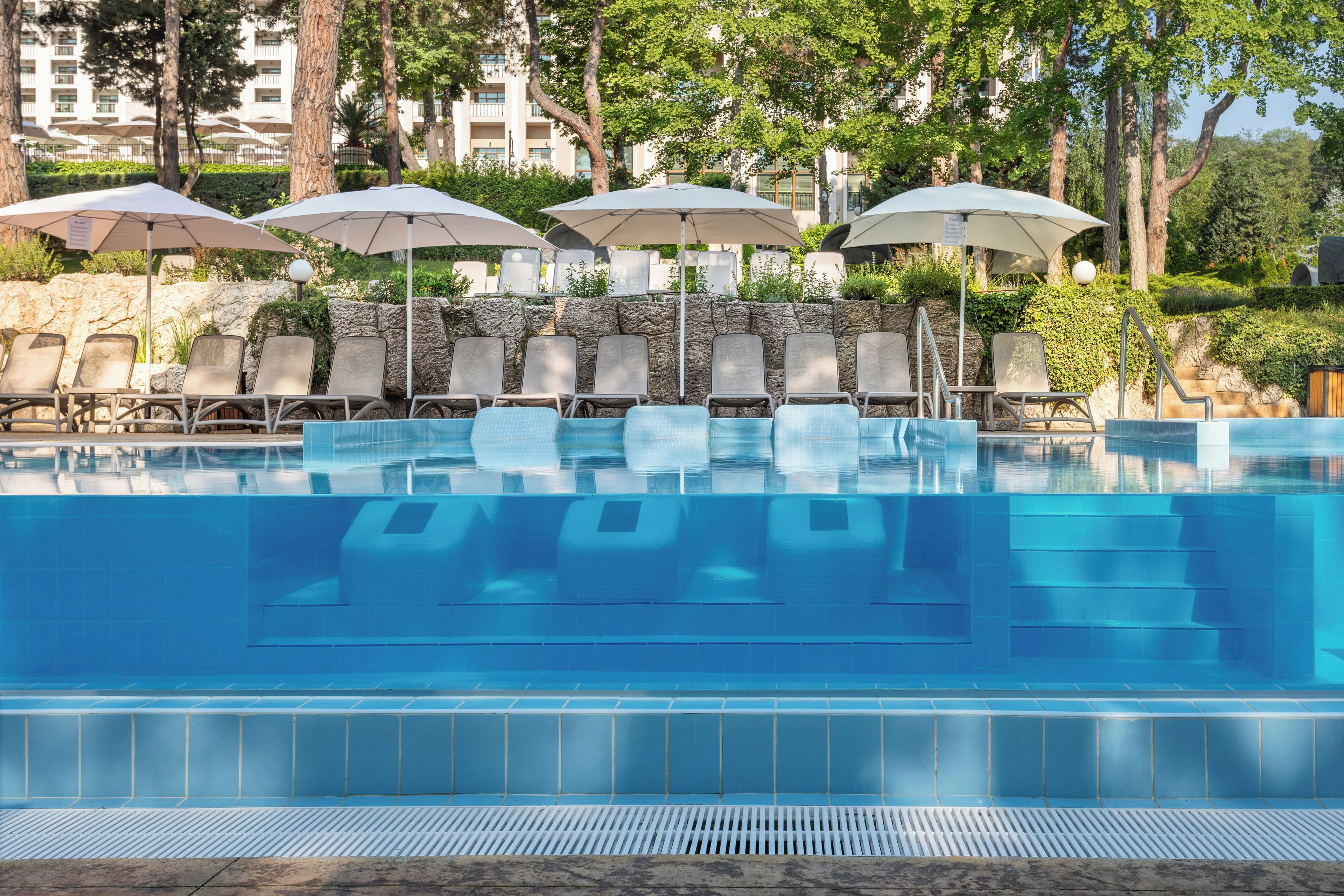 A swimming pool with lounge chairs and umbrellas.
