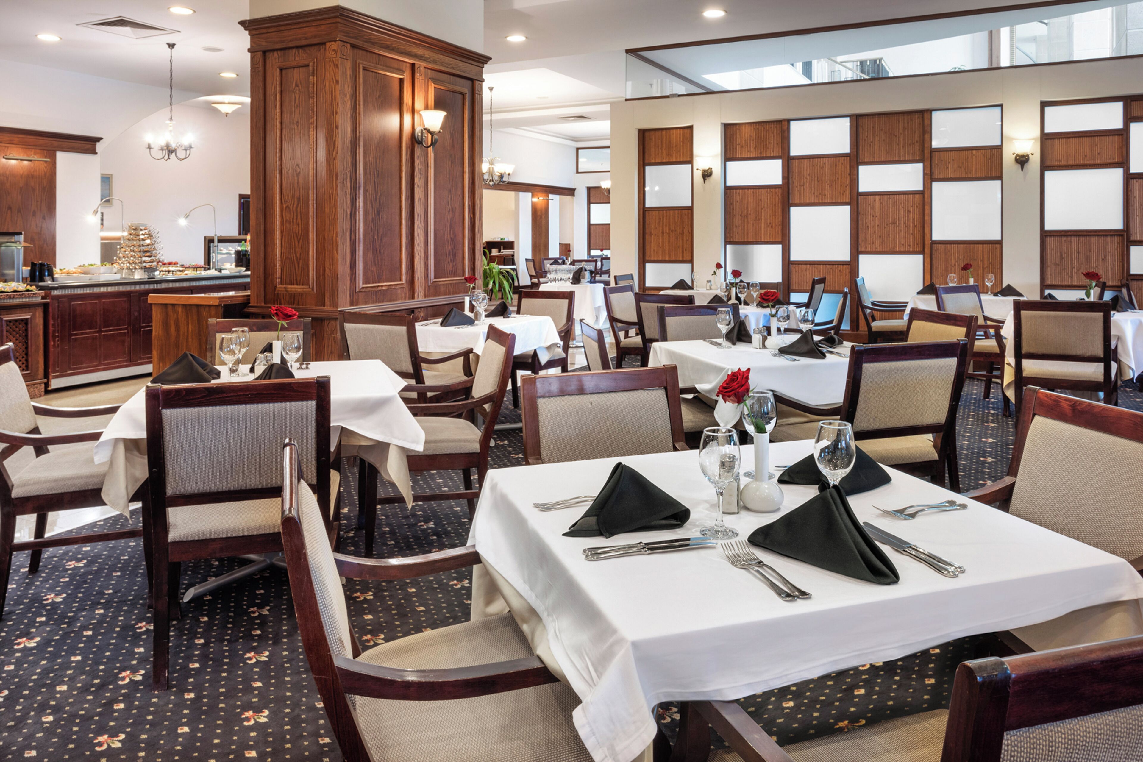 A restaurant with multiple tables, each set with white tablecloths, black napkins, and silverware.