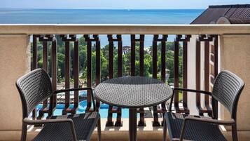 A balcony with a view of a swimming pool and the sea.