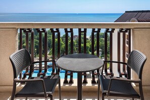A balcony with a view of a swimming pool and the sea.