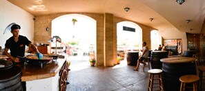 A restaurant with a rustic interior, featuring stone arches, wooden tables, and a bar area.