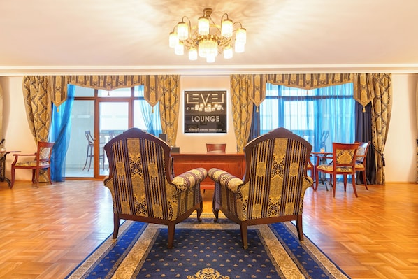 A lounge area with two armchairs, a wooden floor, and a chandelier.