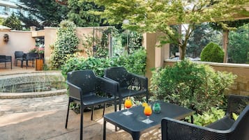 An outdoor patio with a pool, black metal chairs, and tables.