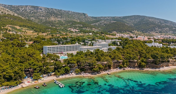 An aerial view of a coastal hotel with a swimming pool, surrounded by lush greenery and mountains. - Bluesun Hotel Elaphusa (Bol)