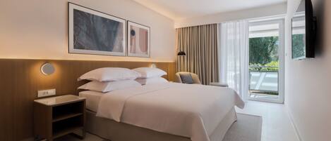 Een moderne hotelkamer met een groot bed, een nachtkastje, een flatscreen televisie aan de muur en een raam met gordijnen.