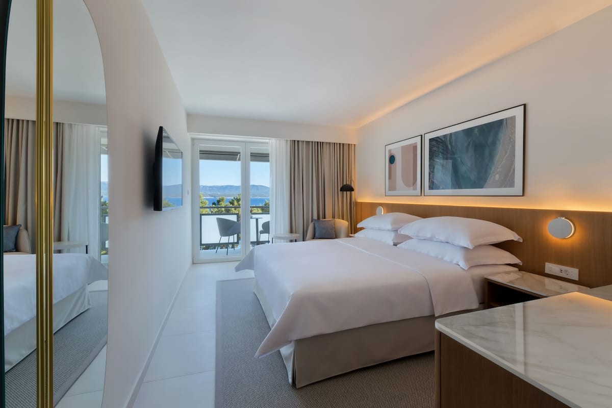 Une chambre d’hôtel moderne, dotée d’un grand lit, d’un bureau et offrant une vue sur l’extérieur.