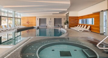 Una piscina interior moderna con sillones de descanso y zona de sauna.