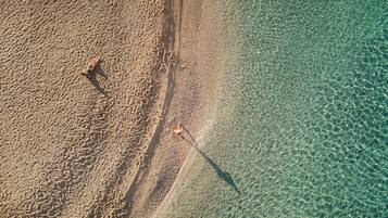 An aerial view of a beach with clear water and sand.