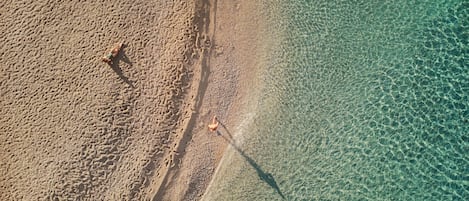 Vista aérea de una playa con agua cristalina y arena.