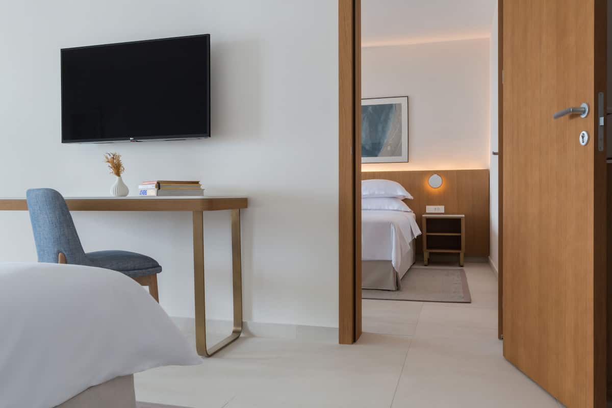 Une chambre d’hôtel comprenant un lit, un bureau avec une chaise, une télévision et une table de chevet avec une lampe.