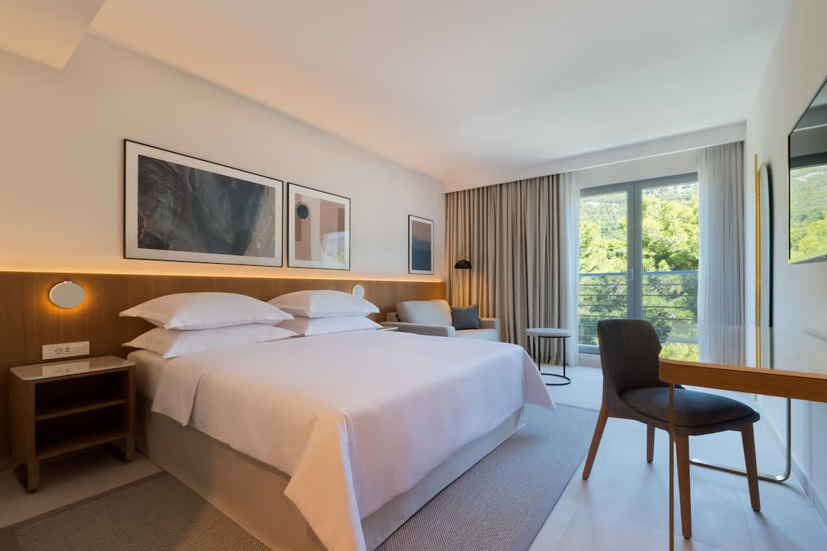Une chambre d’hôtel moderne, dotée d’un grand lit, d’un bureau et offrant une vue sur l’extérieur.