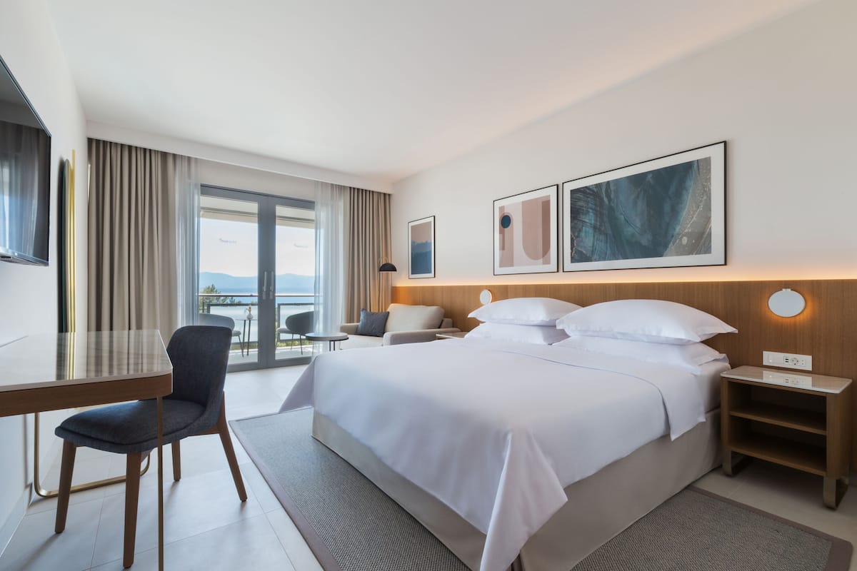 Une chambre d’hôtel moderne, dotée d’un grand lit, d’un bureau, d’une chaise et offrant une vue sur l’extérieur.