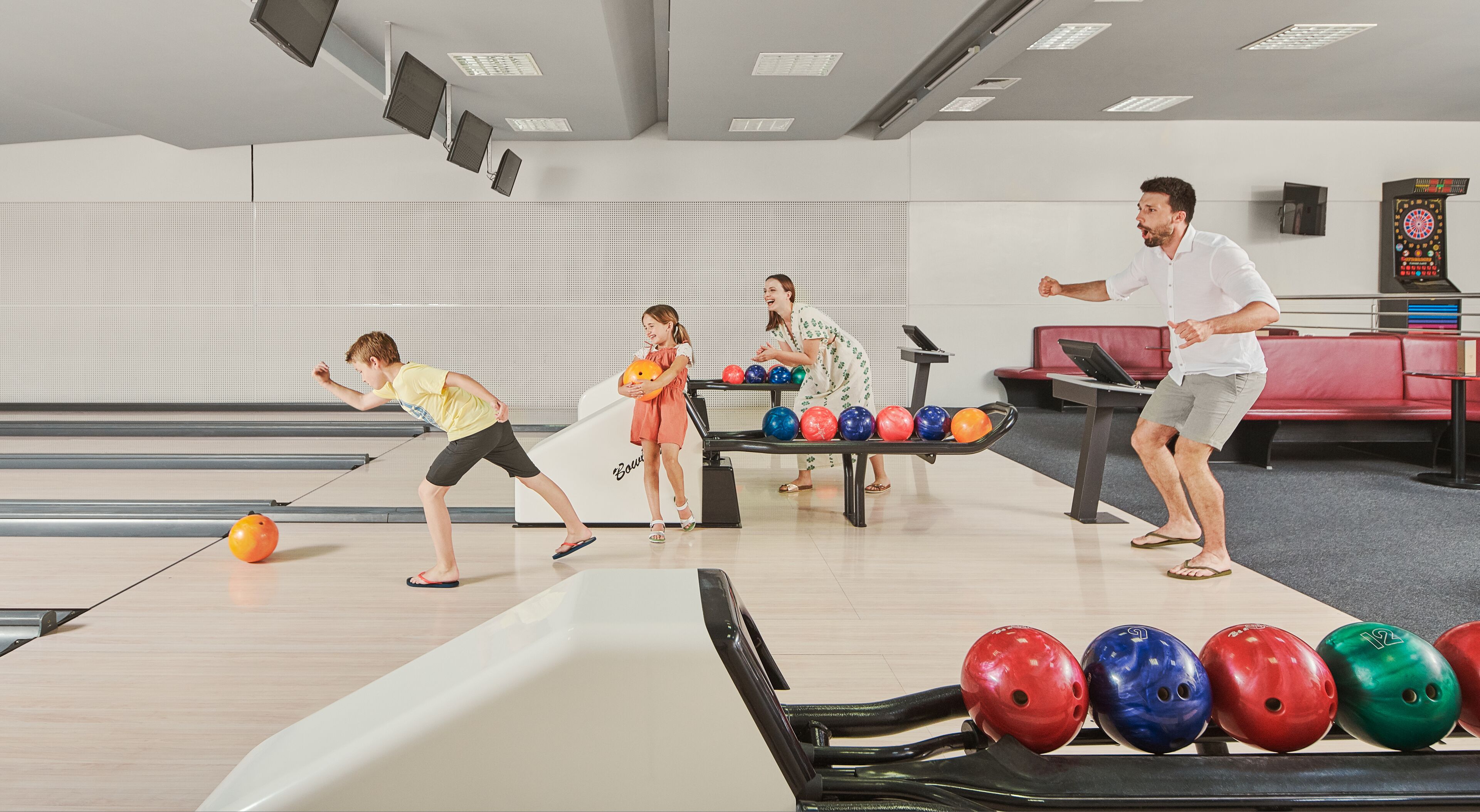 A bowling alley with lanes, a bowling ball, and several bowling pins.