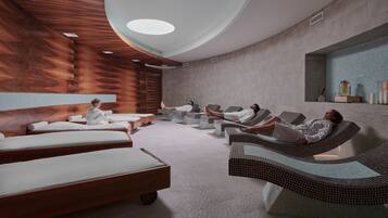 Relax in a serene space with six reclining chairs, each with a footrest and pillow, surrounded by a geometric pattern and natural light from the skylight.