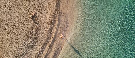 Vista aérea de una playa con agua cristalina y arena.