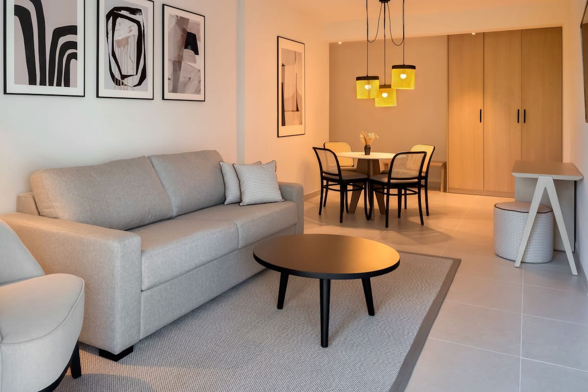 Ein modernes Wohnzimmer mit einer Couch, einem runden Couchtisch und einem Essbereich mit Stühlen und einem Tisch.