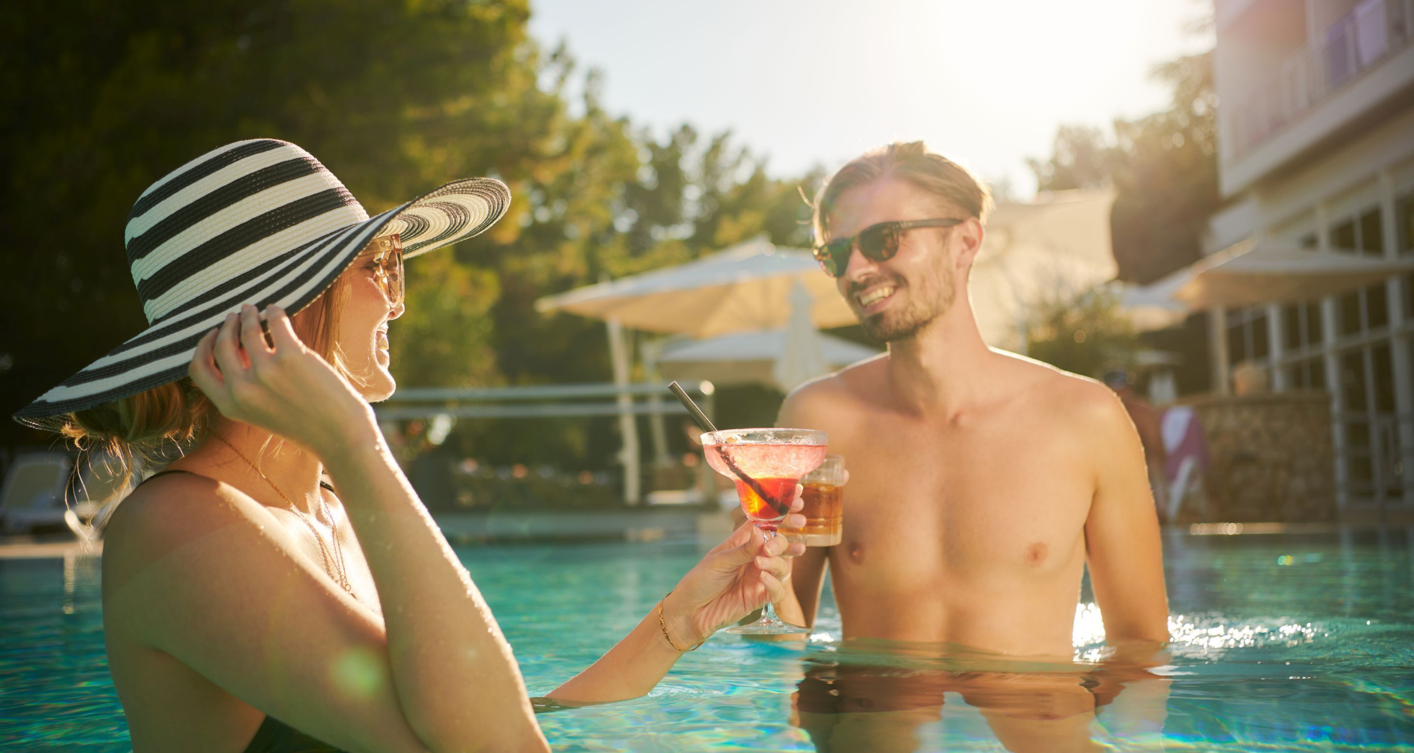 A poolside scene with a person holding a drink.
