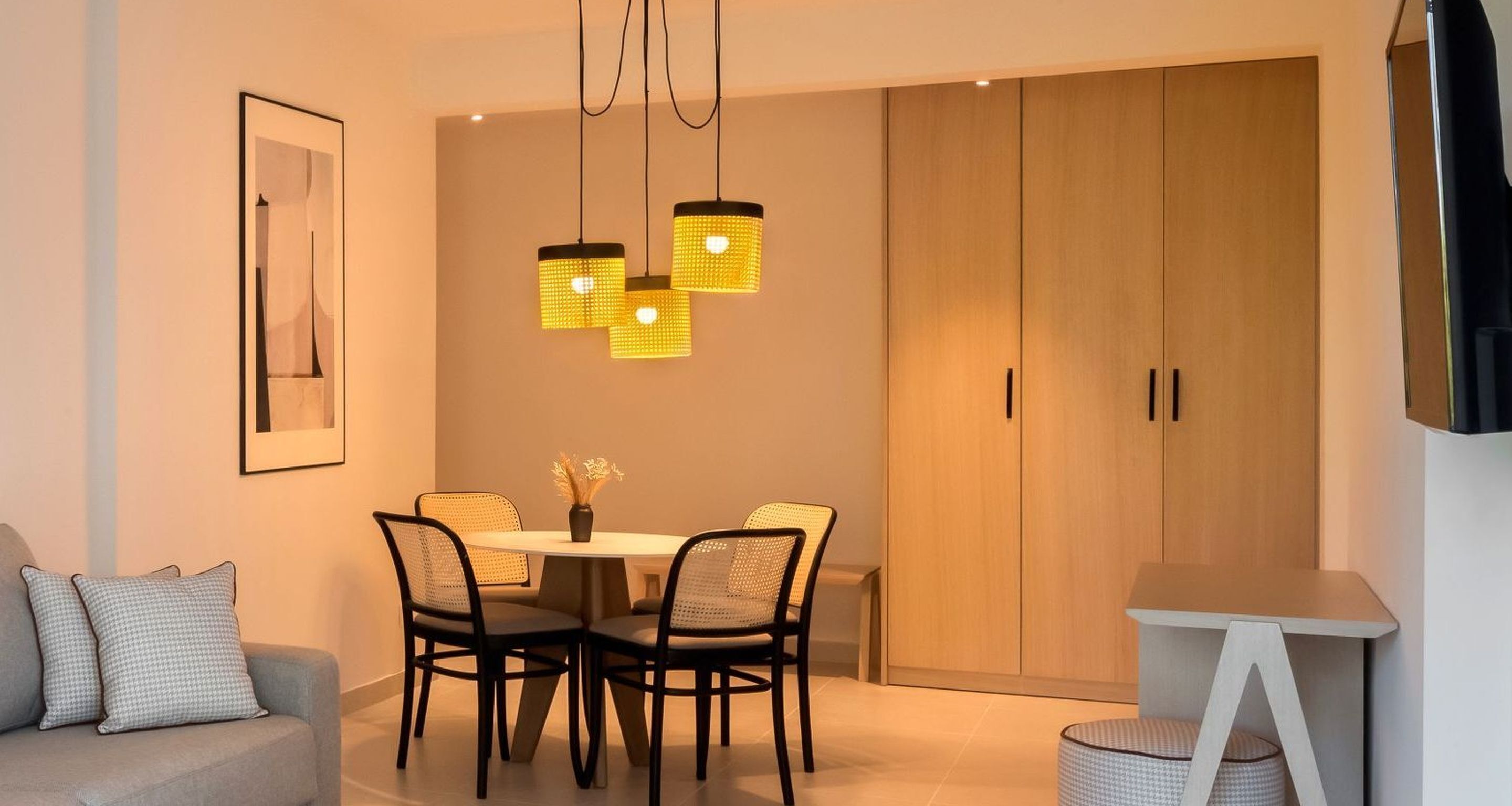 Un comedor moderno con una mesa redonda, cuatro sillas y una lámpara colgante.