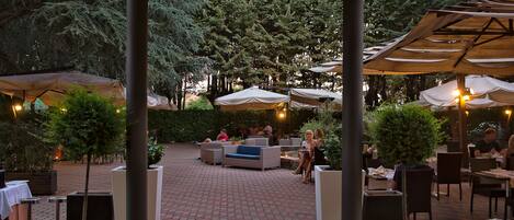 An outdoor patio with seating areas, umbrellas, and potted plants.