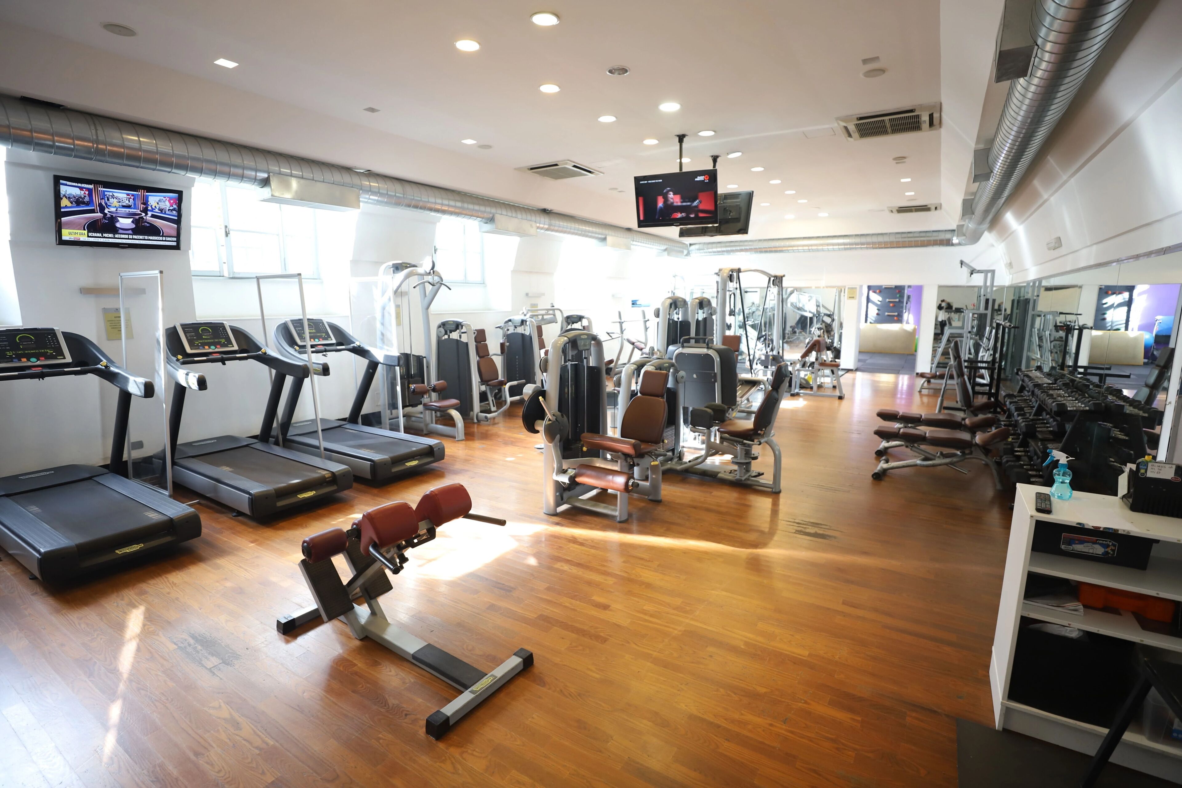 Un gimnasio con cintas de correr, máquinas de pesas y una pantalla de televisión.