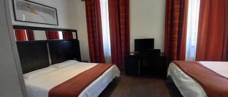 Quarto de hotel com duas camas, televisão e escrivaninha.
