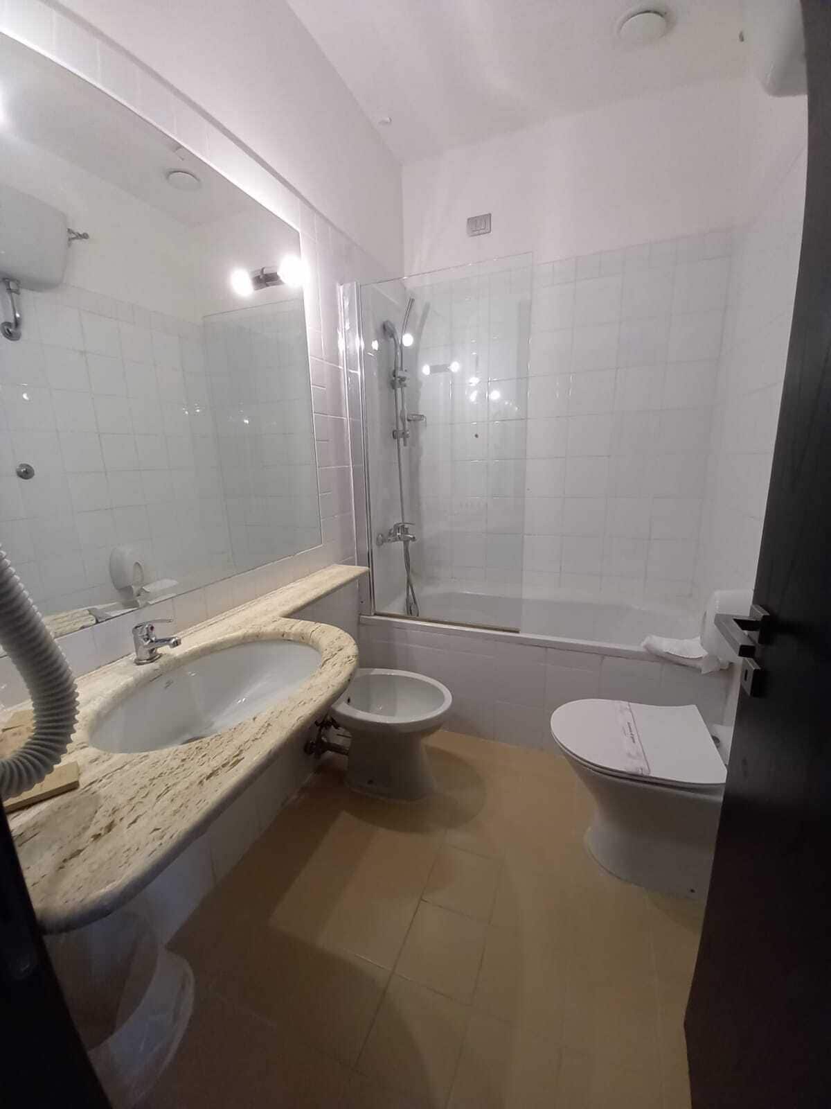 A bathroom with a marble sink, a toilet, a bidet, and a glass-enclosed shower.