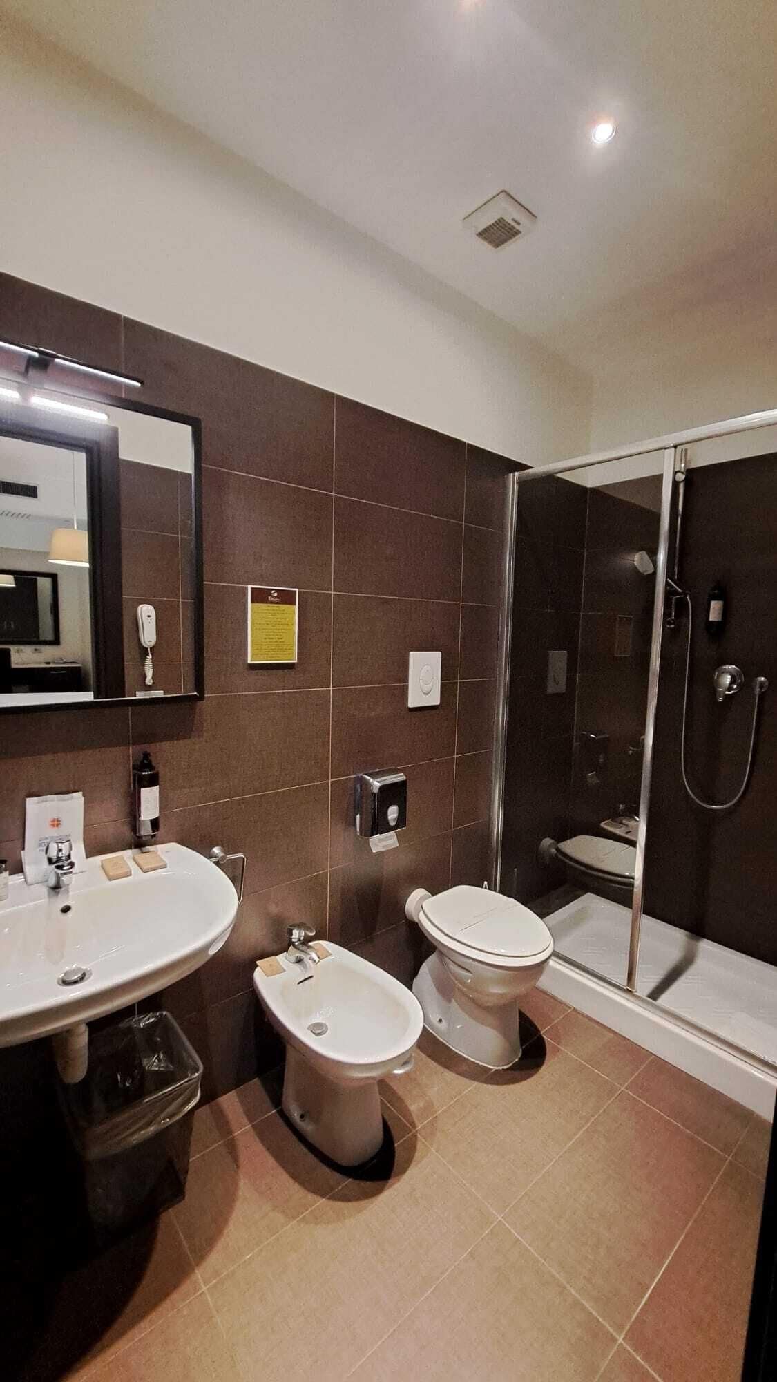 A modern bathroom with a sink, bidet, toilet, and a glass-enclosed shower area.