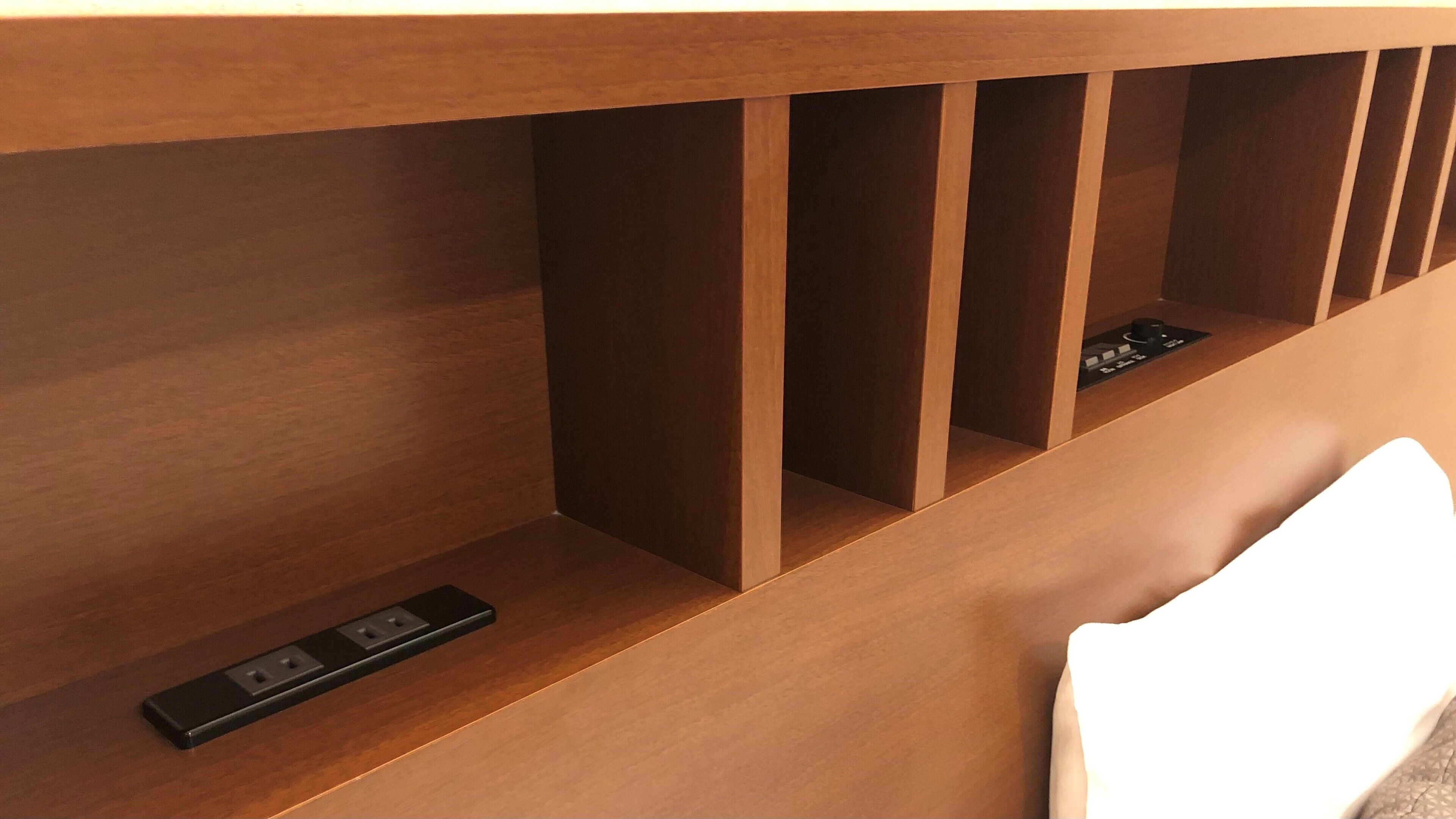 Un escritorio de madera con varios compartimentos y una regleta eléctrica.