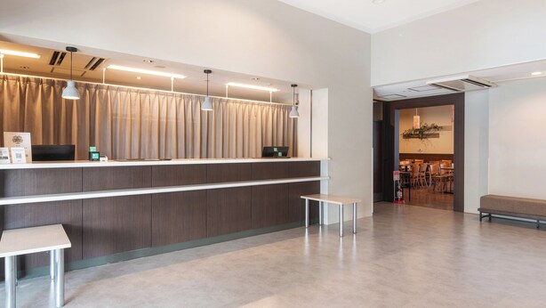 A modern reception area with a counter, computer, and seating. - Vessel Hotel Fukuoka Kaizuka (Fukuoka)