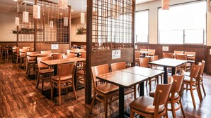 A restaurant interior with wooden tables and chairs, a wooden floor, and a decorative partition with hanging lights. - Vessel Hotel Fukuoka Kaizuka (Fukuoka)