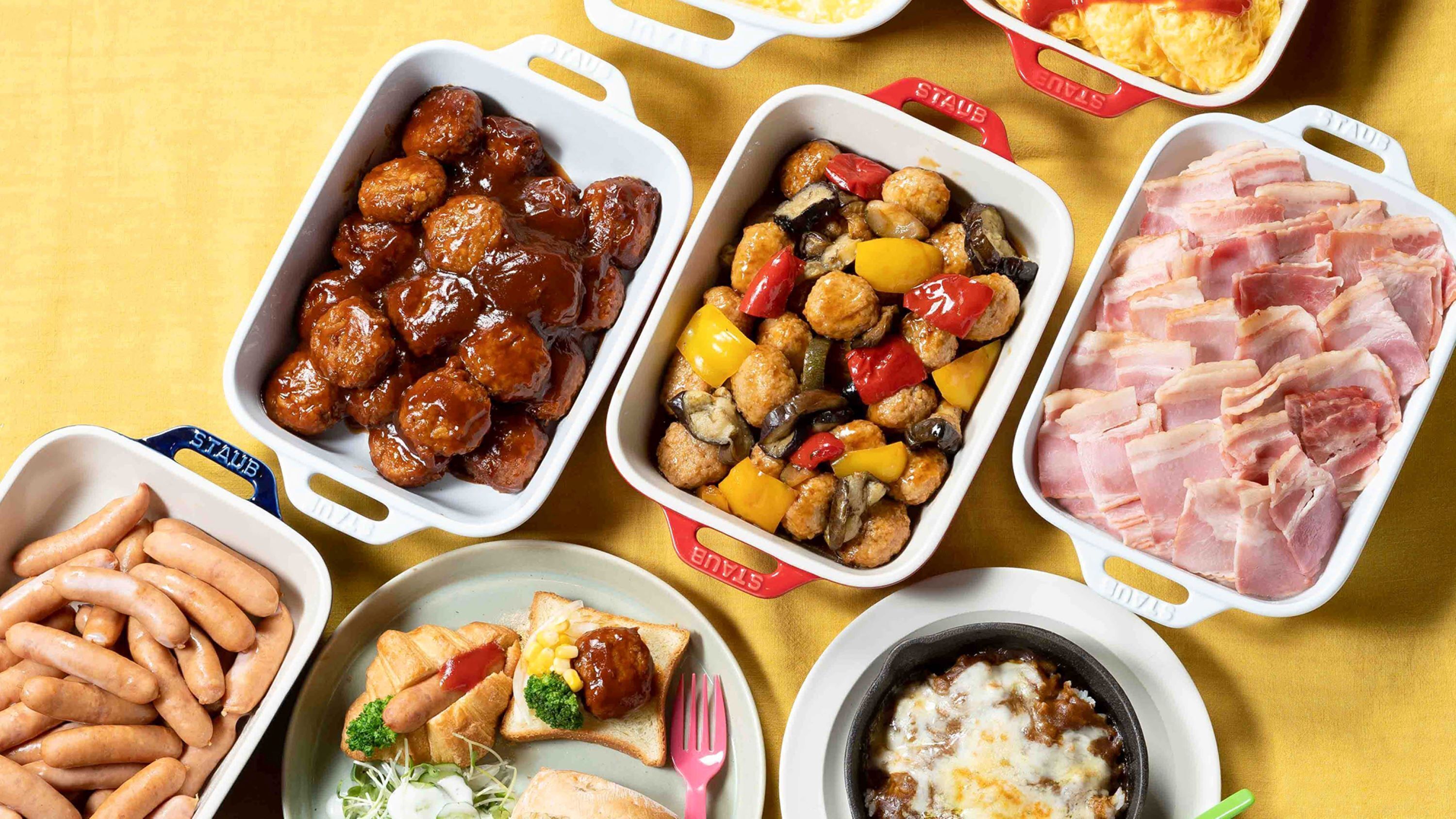 A variety of food items in different containers, including sausages, meatballs, vegetables, and a dish with cheese.