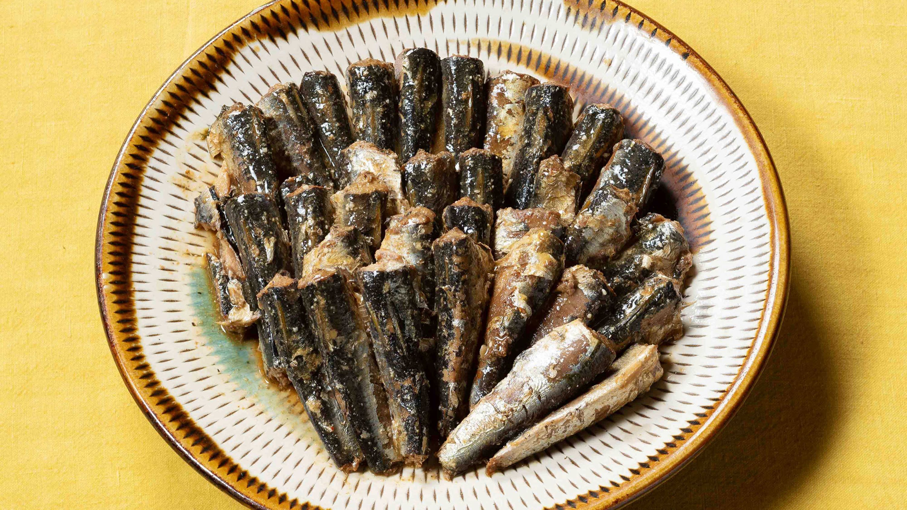 Un plato de sardinas a la parrilla sobre un plato de cerámica con textura.