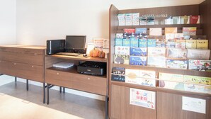 A hotel reception desk with a computer, a printer, and a display of travel brochures. - Vessel Hotel Fukuoka Kaizuka (Fukuoka)