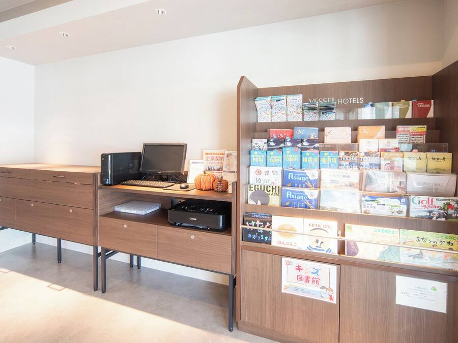 A hotel reception desk with a computer, a printer, and a display of travel brochures.