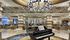 Eine großzügige Lobby mit einem Flügel, Sitzbereichen und einem Chandelier.