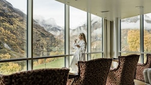 A room with large windows offering a view of a mountainous landscape.