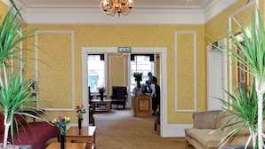 A spacious lobby with a chandelier, seating area, and potted plants. - Grange Buckingham (London)