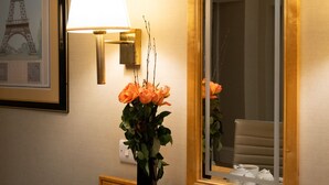 A breakfast tray with croissants and coffee cups on a wooden table, a vase with orange flowers, a wall-mounted lamp, and a framed picture of the Eiffel Tower. - Grange Buckingham (London)