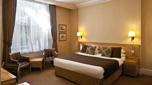 A hotel room with a large bed, two bedside tables, a chair, and a window with curtains. - Grange Buckingham (London)