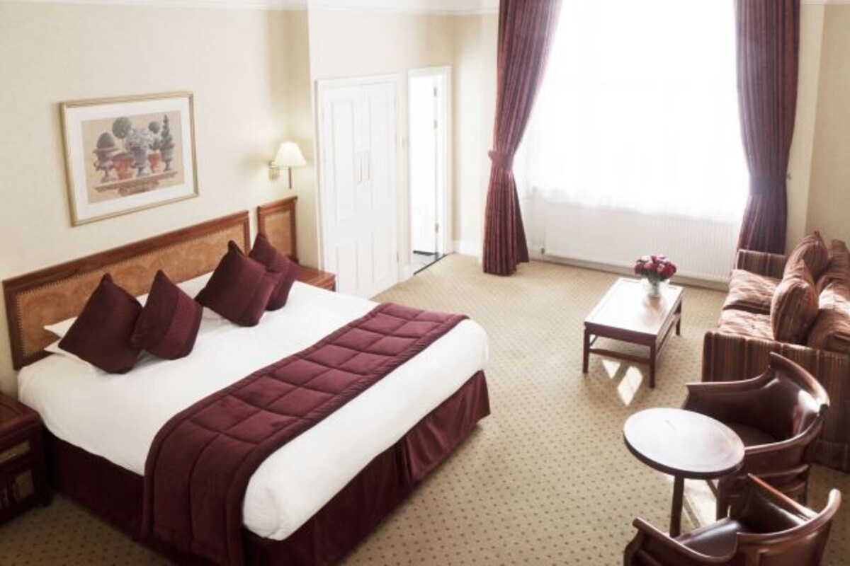 Une chambre d’hôtel avec un grand lit, une petite table, un canapé et une chaise.